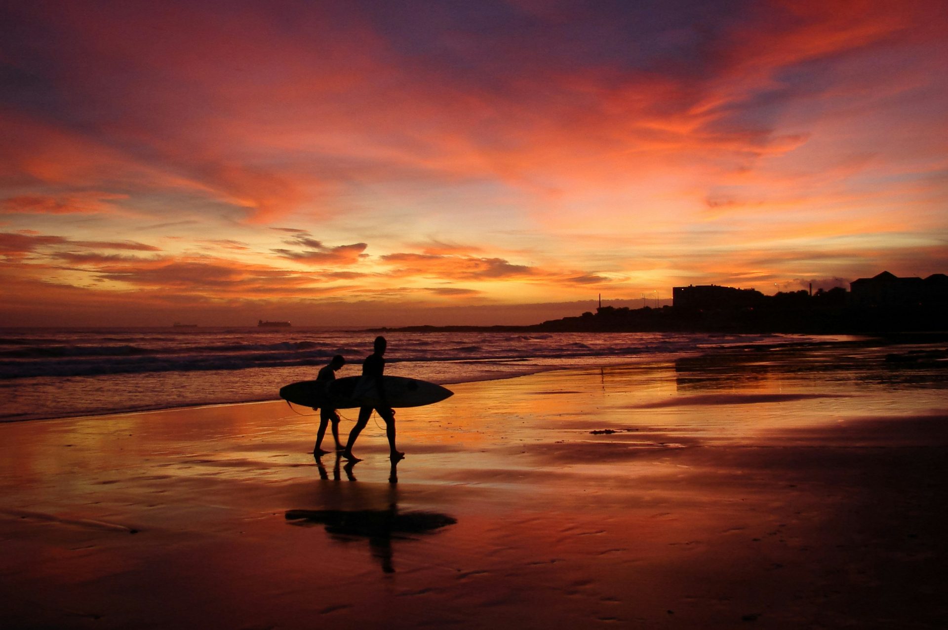 silhouette of man carrying surfboard during sunset